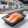 Fresh salmon fillets in sealed black PP tray displayed in a modern supermarket deli section