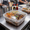 Mini PE cling film applied to food delivery containers in a commercial kitchen for spill prevention and hygiene