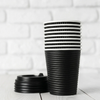 Wholesale black and maroon double wall ripple paper coffee cups with lids on a white wooden background