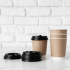 Wholesale black and maroon double wall ripple paper coffee cups with lids on a white wooden background